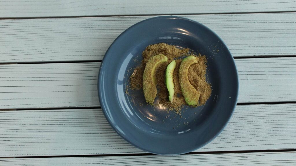 sliced avocado rolled in ground flax for baby