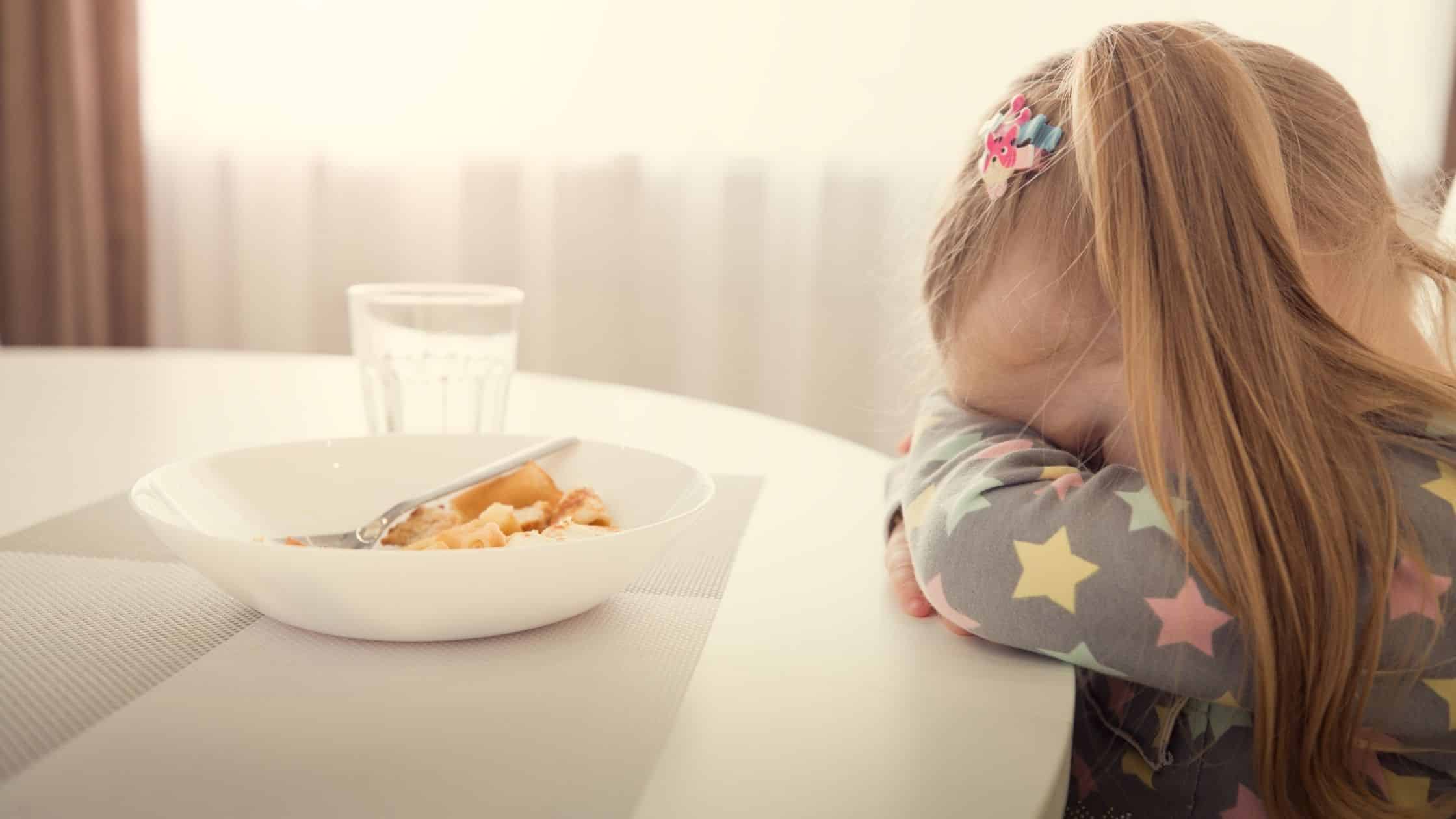 unhappy child at dinner table