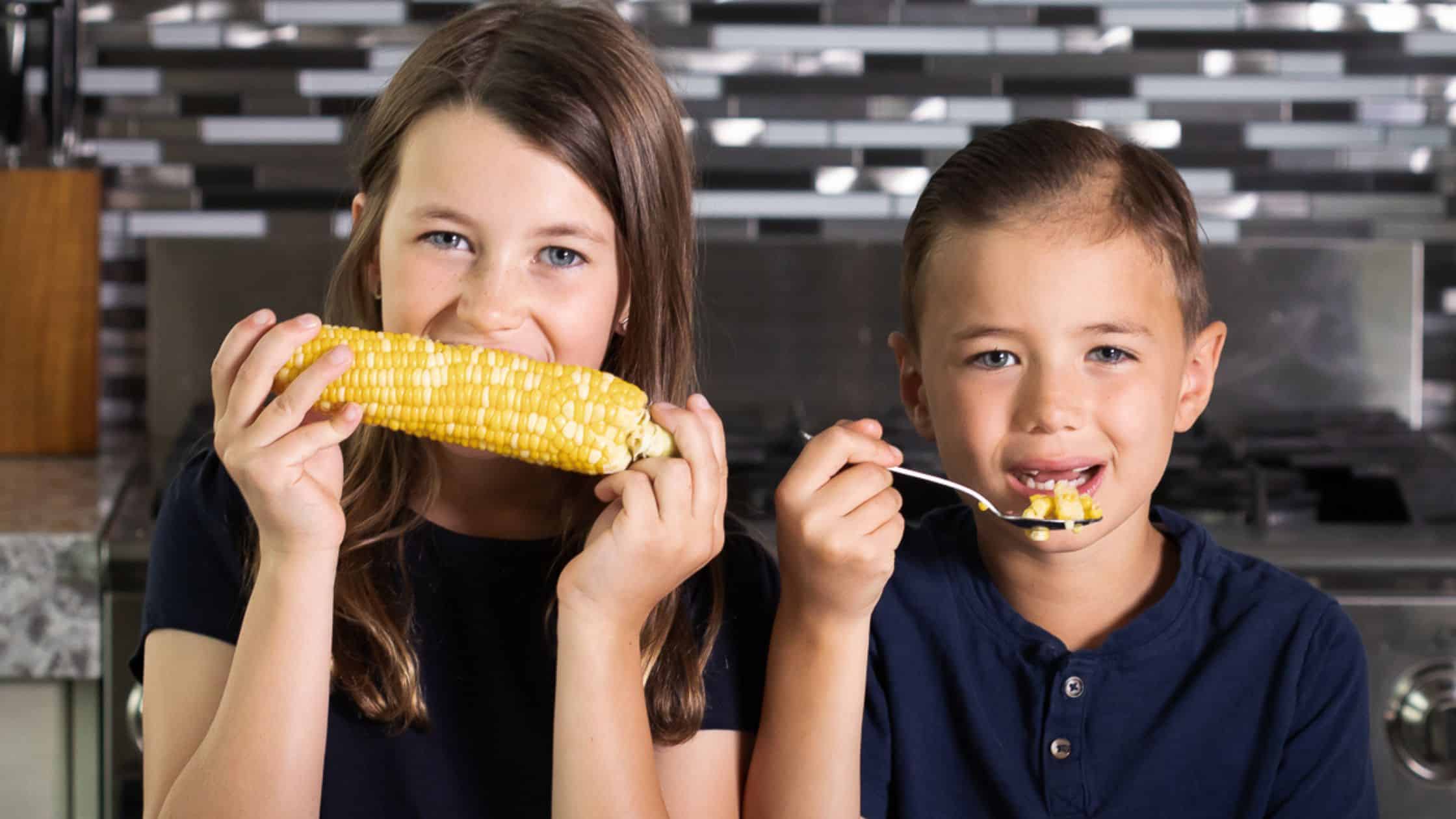 two children eating corn