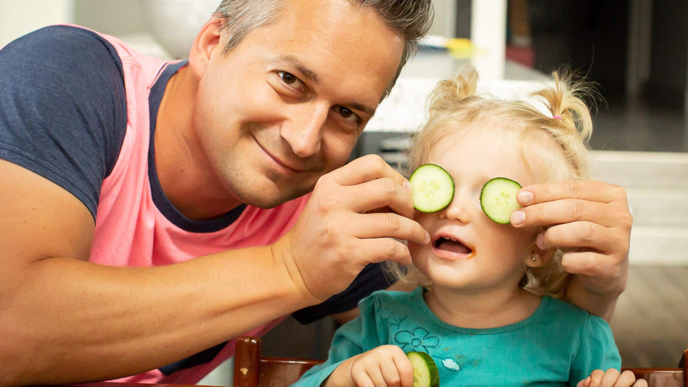 little girl holding cucumbers up to her eyes